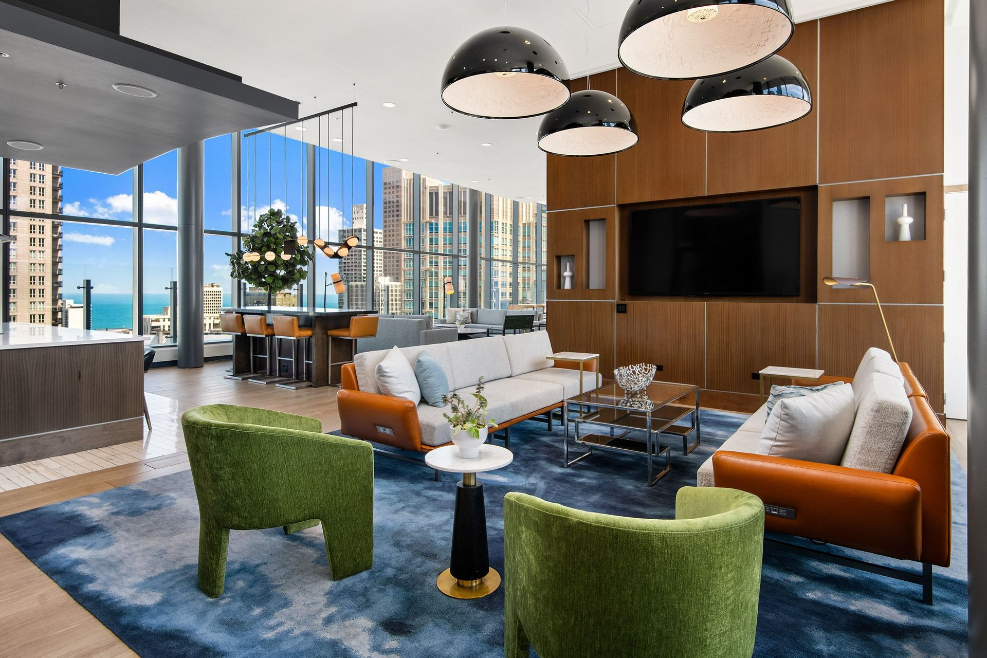 Modern living room with blue rug, orange and green chairs, glass coffee table, and city skyline views