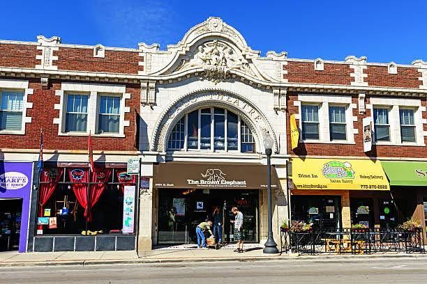 A two-story, red-brick commercial building with arched central windows, featuring a “The Artful Elephant” storefront.
