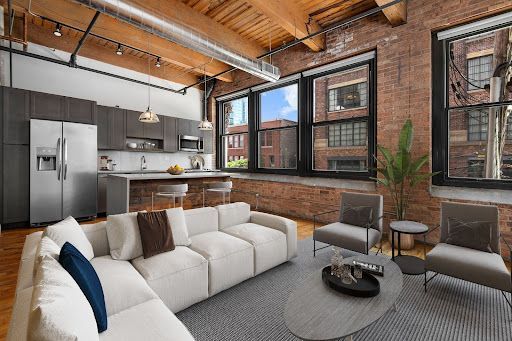 A living room with a couch, chairs, a table, and a refrigerator.