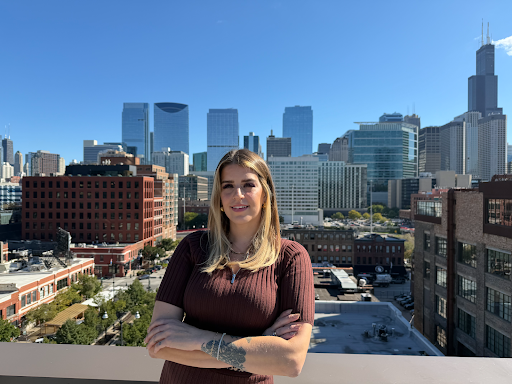 Woman with crossed arms smiles in front of a Chicago skyline on a sunny day.