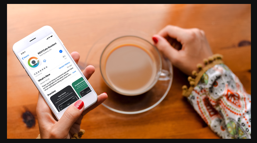 A woman is holding a cell phone next to a cup of coffee.