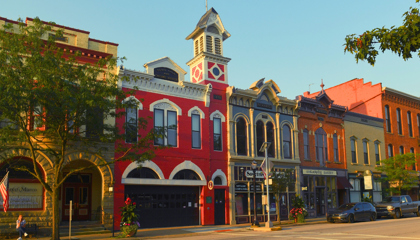 Colorful historic downtown street with ornate brick buildings and a clock tower in warm sunlight