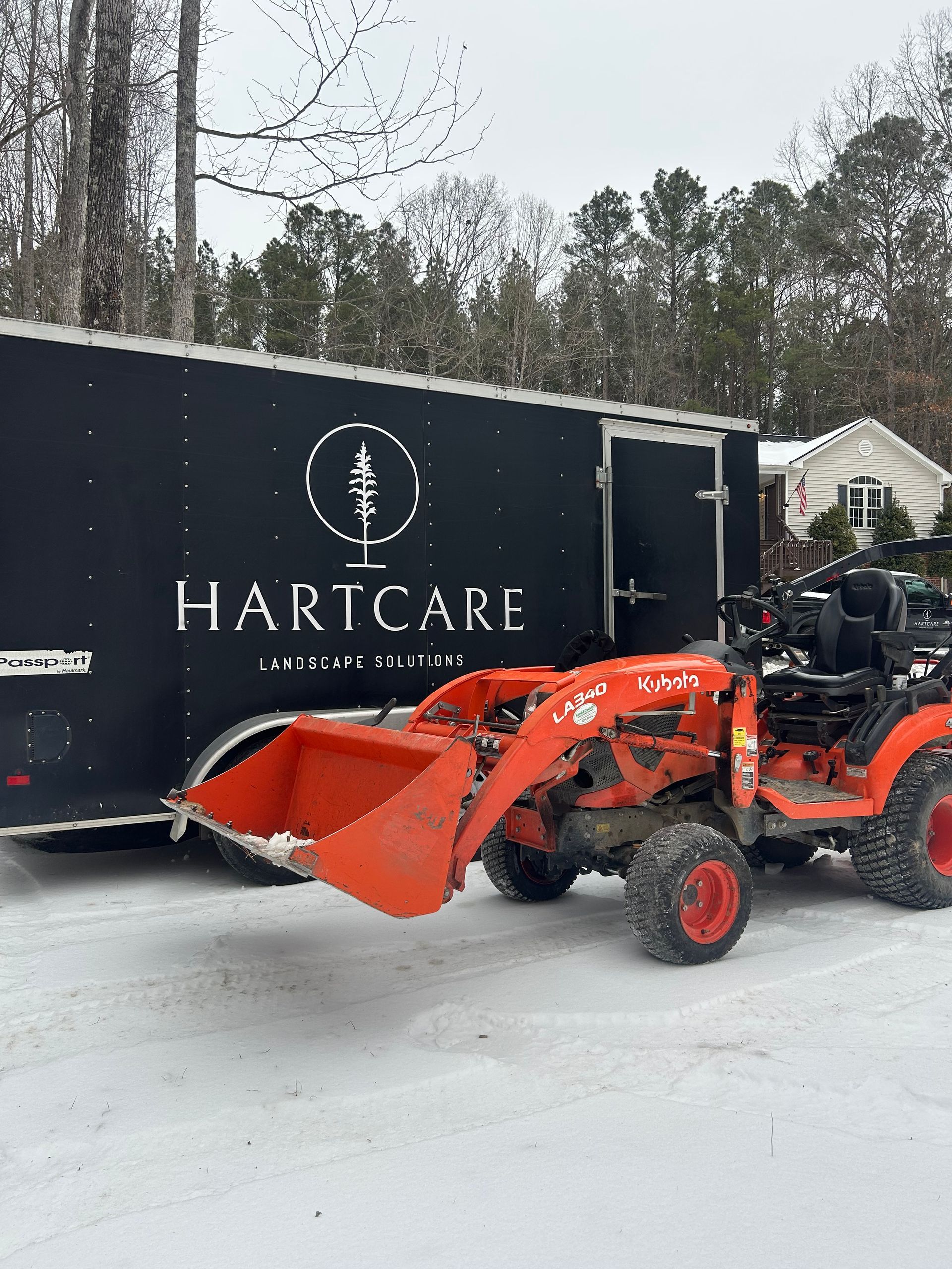 A red snowplow clears deep snow from a road during a winter storm.