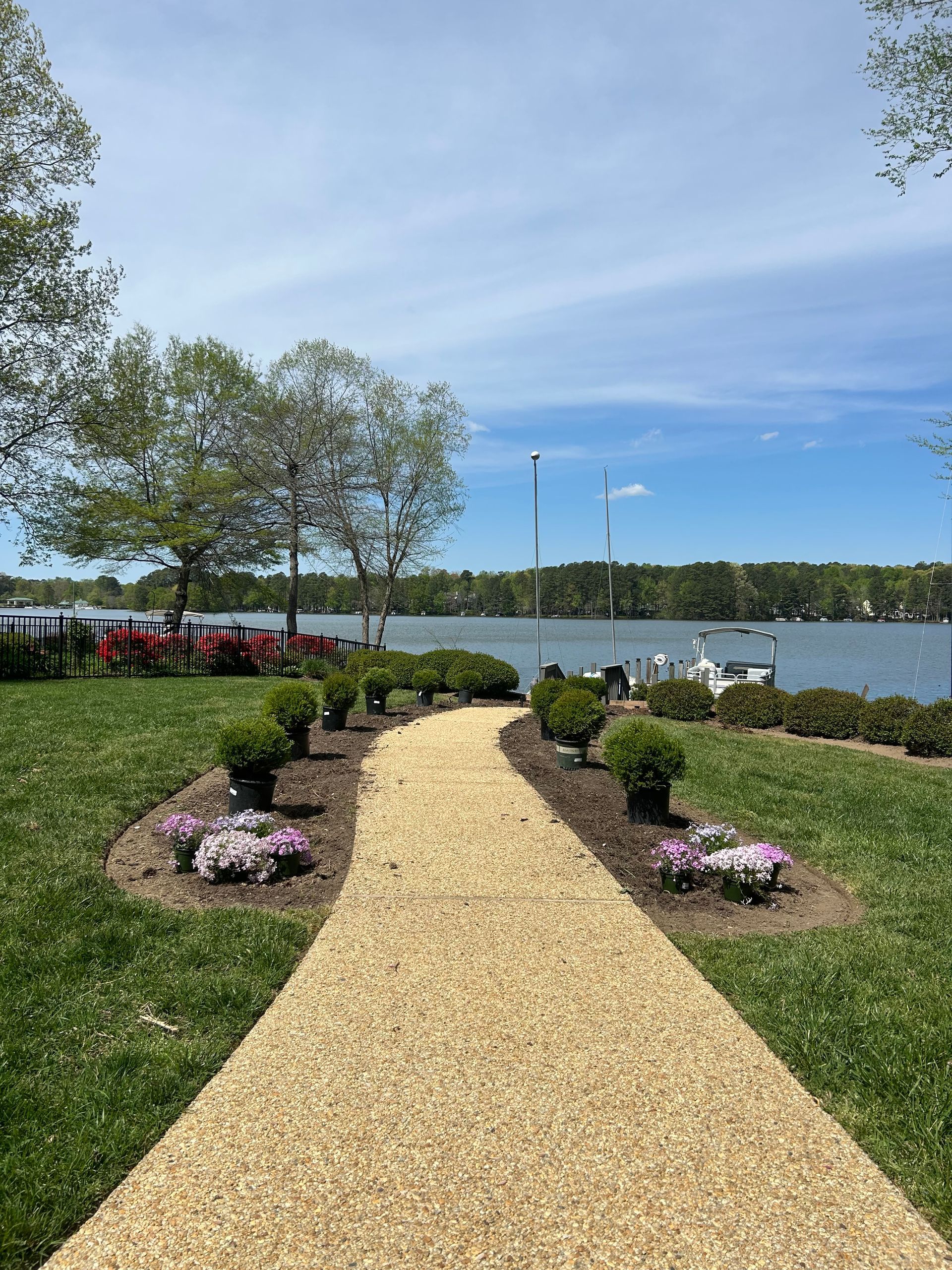 A two-story brick and siding house with a mulched garden bed in the front yard featuring small shrubs.