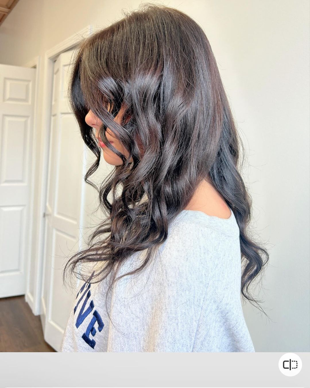 A woman with long dark hair is wearing a gray shirt with the word love on it.