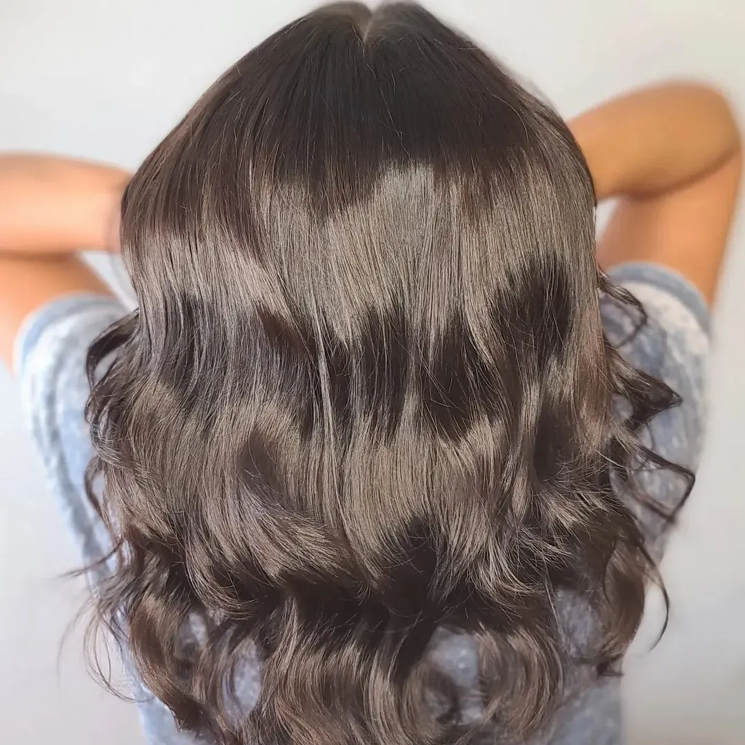 the back of a woman 's head showing her long brown hair