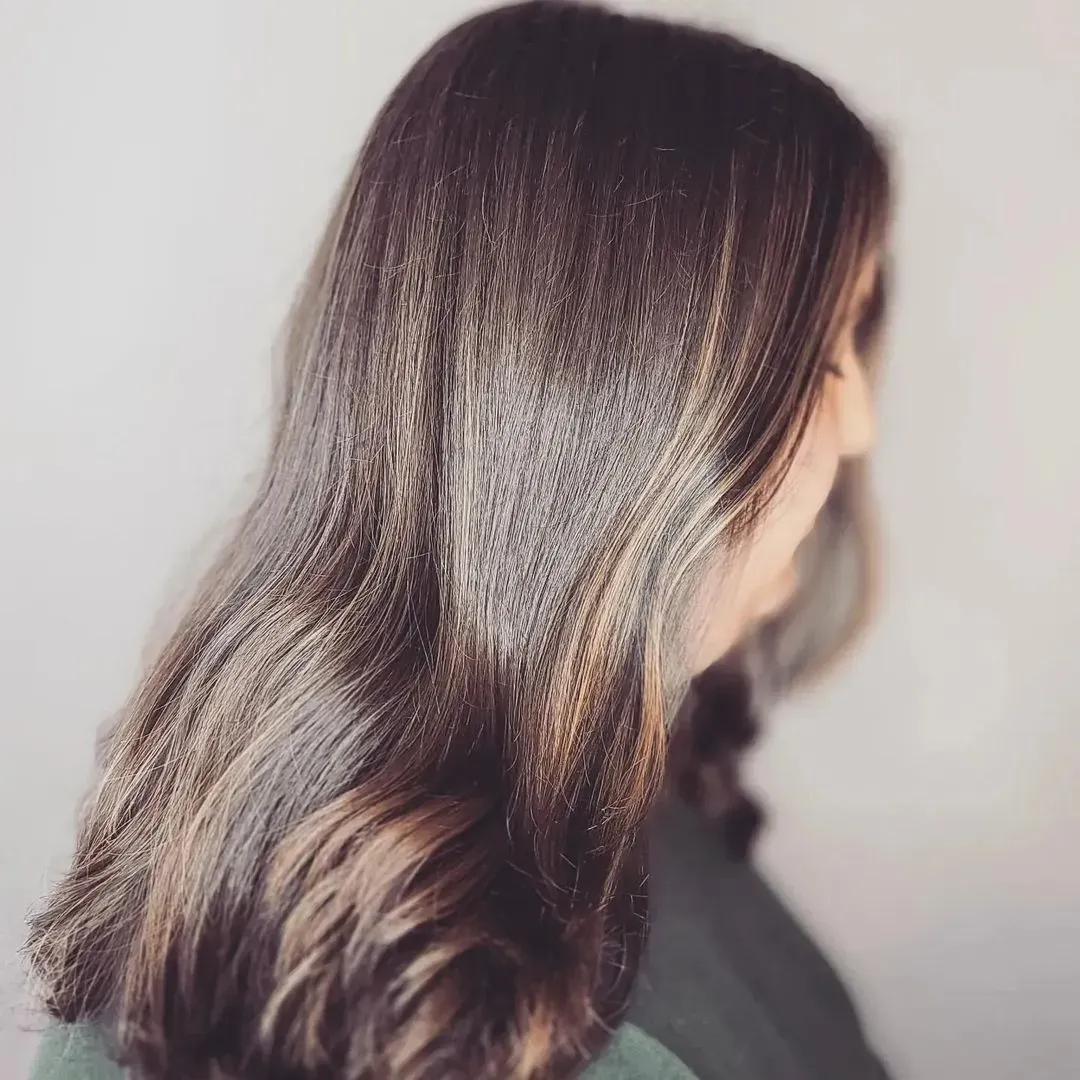 a woman with long brown hair is wearing a green shirt