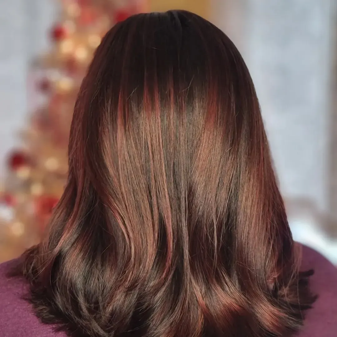 the back of a woman 's hair with a christmas tree in the background