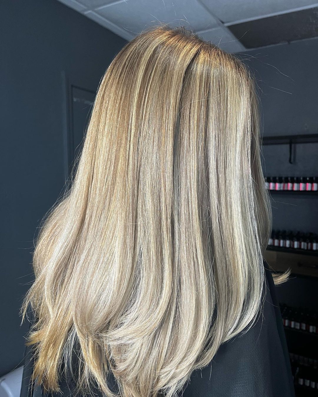 a woman with long blonde hair is wearing a black cape