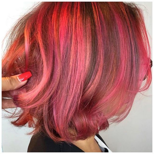 a woman with short pink hair has red highlights