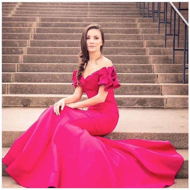 a woman in a long pink dress sits on a set of stairs
