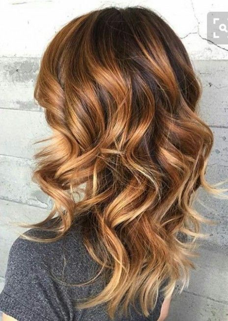 a woman with long wavy brown hair is wearing a grey shirt