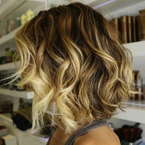 a woman with short wavy hair is wearing a gray tank top .
