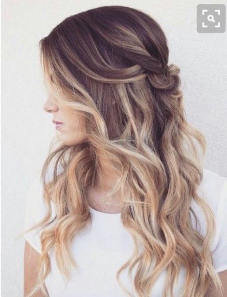 a woman with long wavy hair is wearing a white shirt .