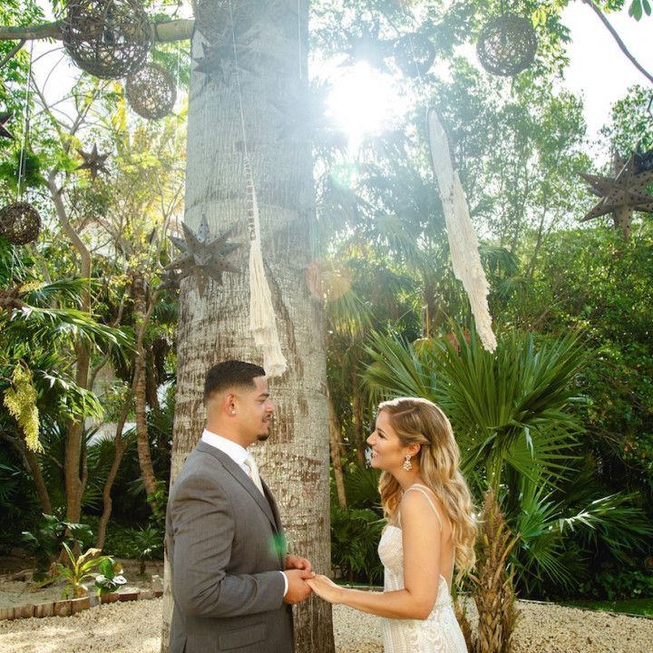 A bride and groom are holding hands in front of a tree