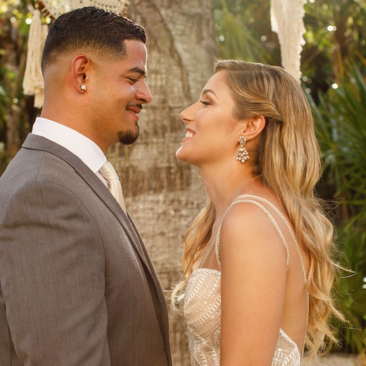 A bride and groom are looking at each other and smiling.