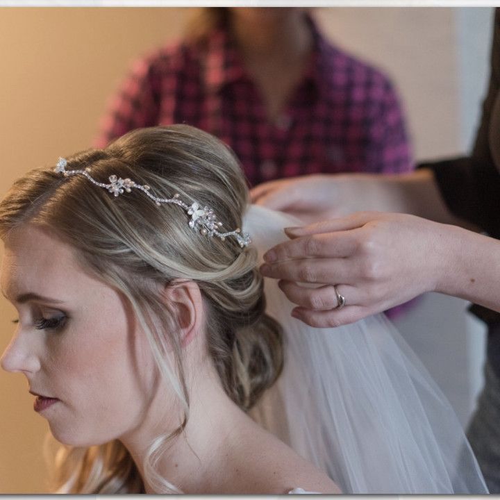 A woman is putting a veil on a woman 's head