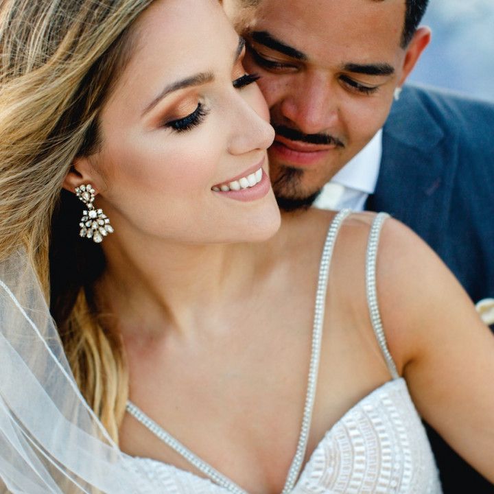 A bride and groom are posing for a picture and the bride is wearing a veil
