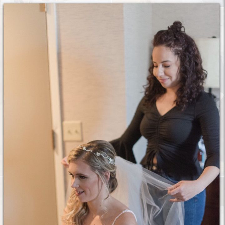 A woman is putting a veil on another woman 's head