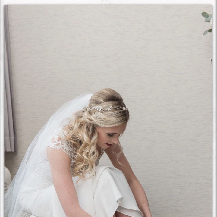 A woman in a wedding dress is kneeling down to put on her shoes