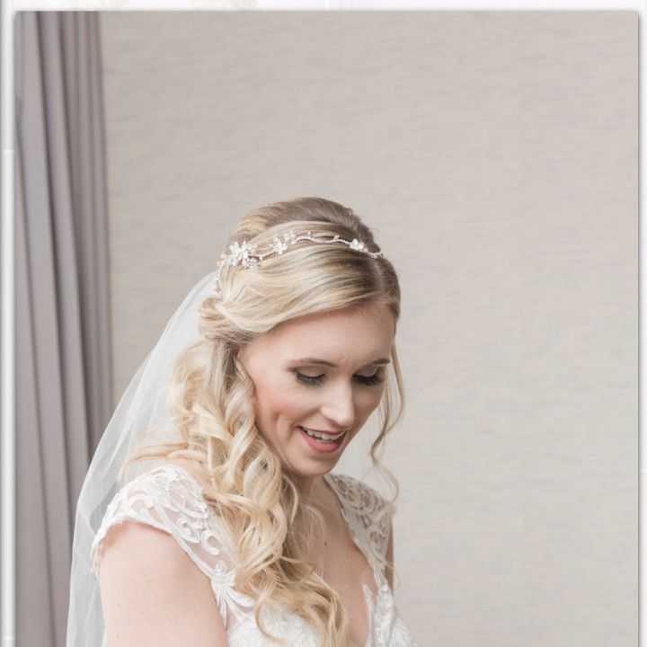 A woman in a wedding dress and veil is smiling