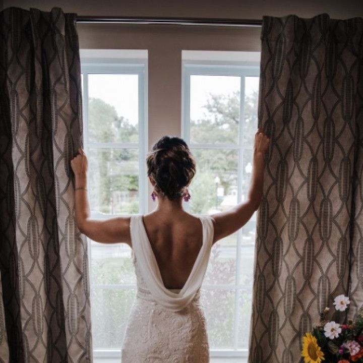 A woman in a wedding dress is looking out a window