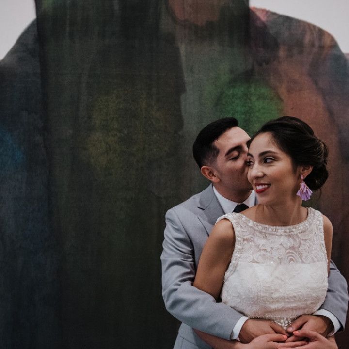 A man kissing a woman on the cheek in front of a painting