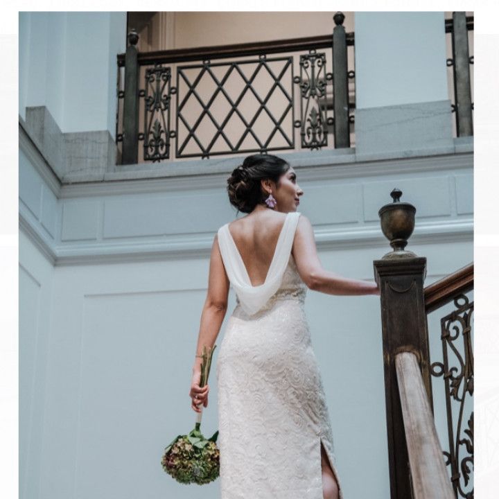 A woman in a white dress is standing on a set of stairs holding a bouquet of flowers