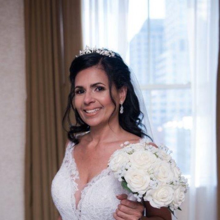 A woman in a wedding dress is holding a bouquet of white roses