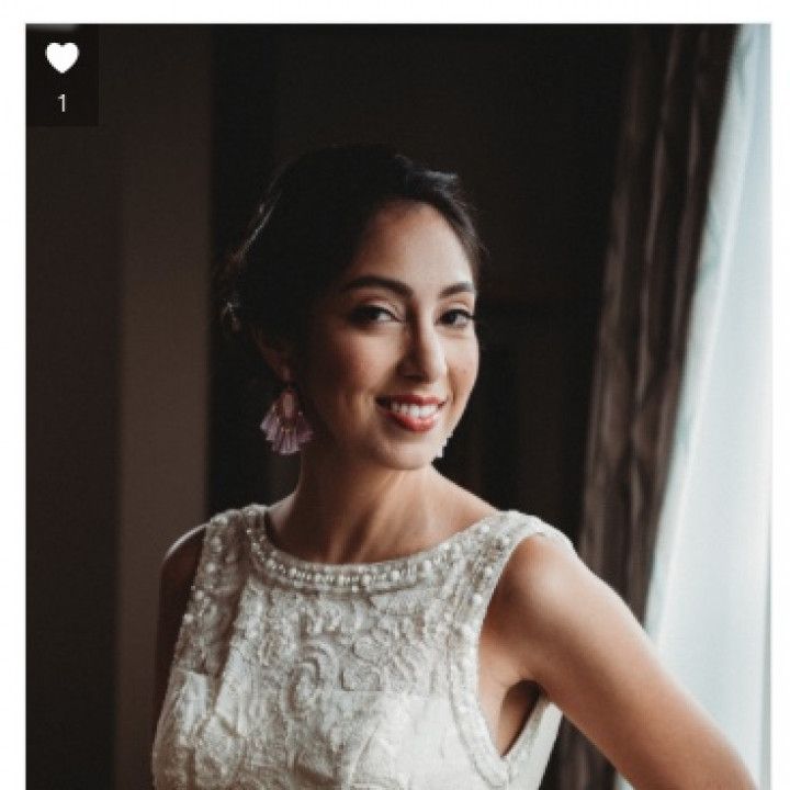 A woman in a white dress is standing in front of a window