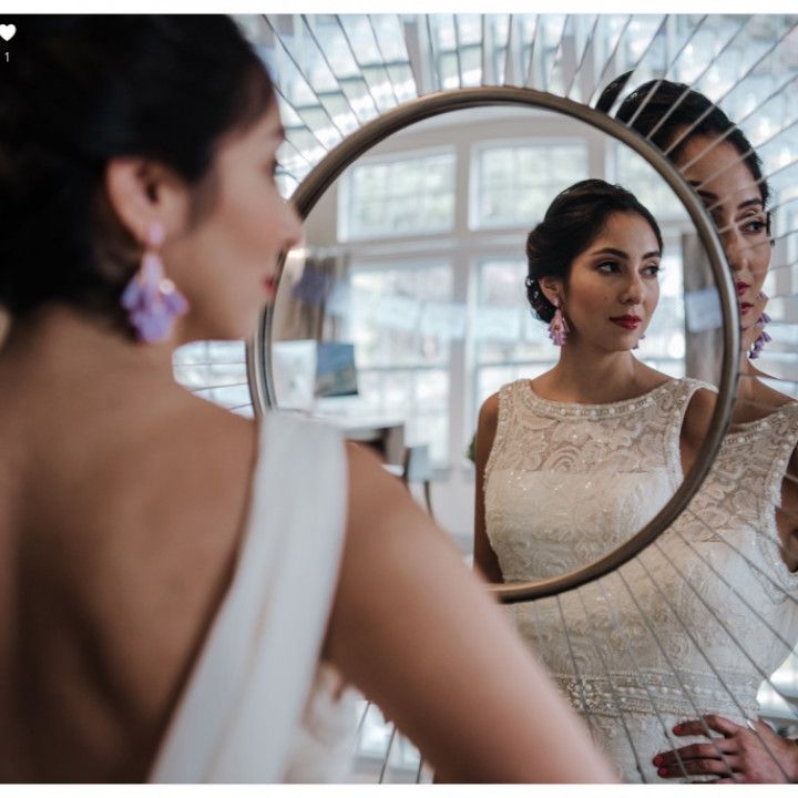 A woman in a white dress is looking at her reflection in a mirror