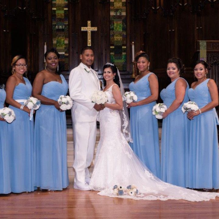 A bride and groom pose with their bridesmaids in front of a cross