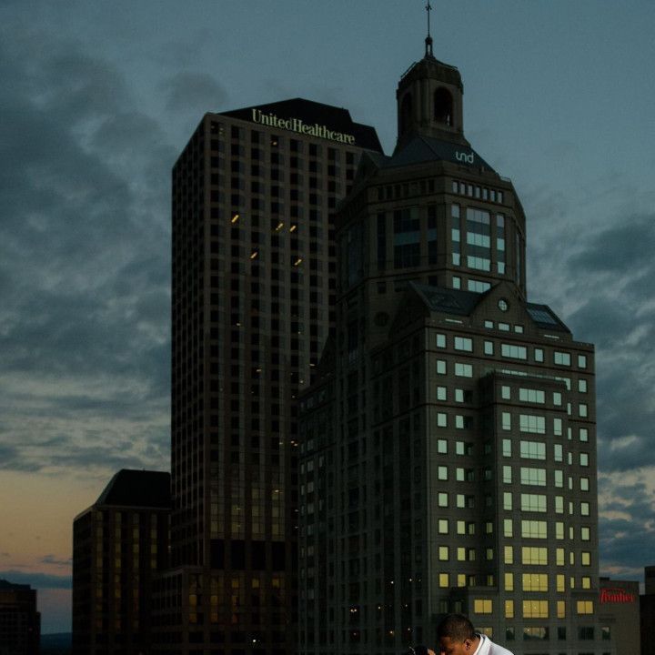 A couple kissing in front of a tall building that says trinity healthcare
