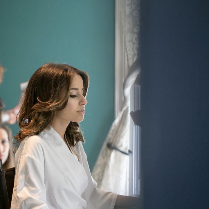 A woman in a white robe is getting her hair done by a hairdresser.