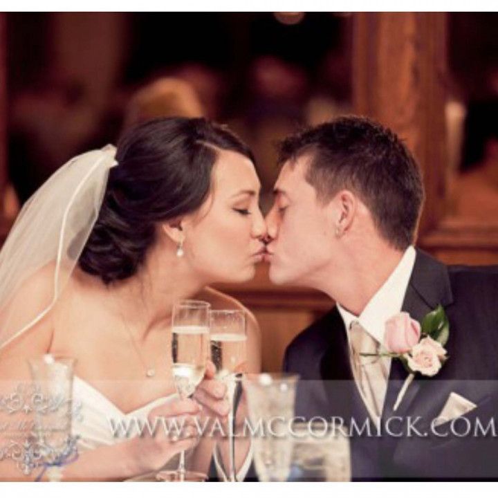 A bride and groom kissing at a table with champagne glasses