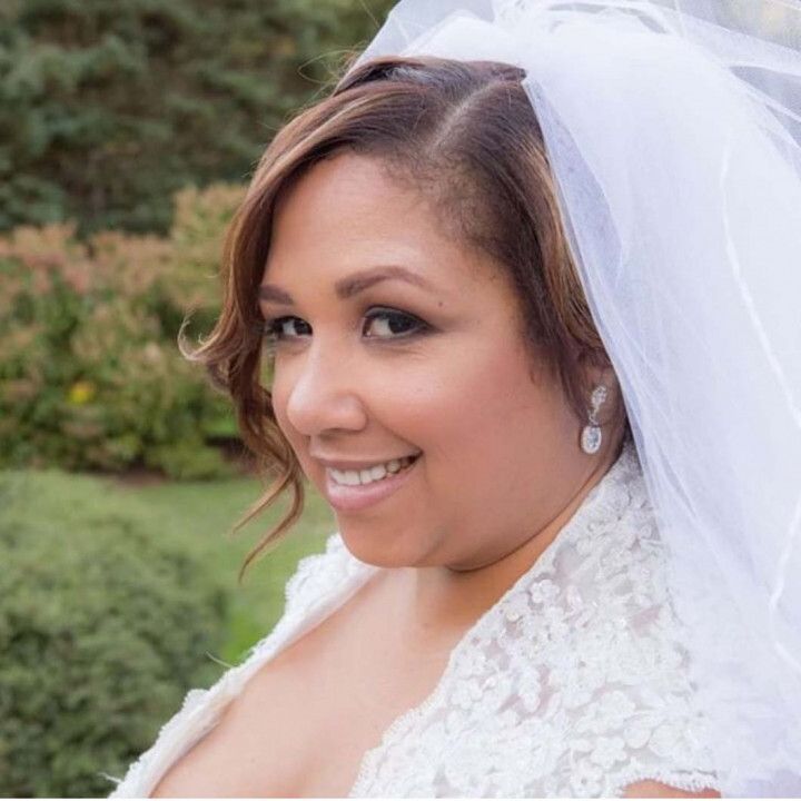 A woman in a wedding dress and veil is smiling