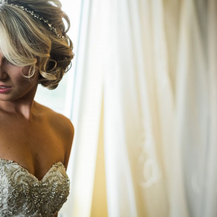 A woman in a wedding dress is standing in front of a window