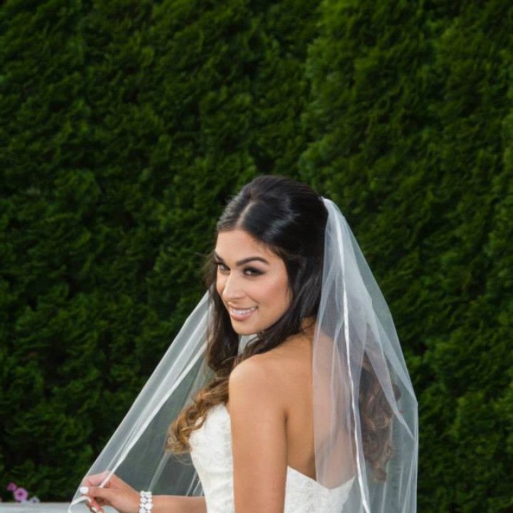 A woman in a wedding dress and veil is smiling