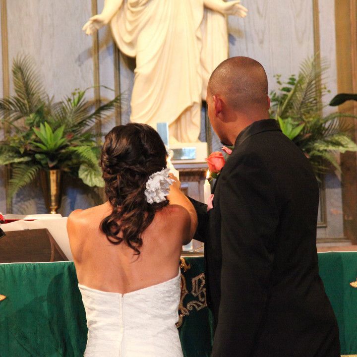 A bride and groom stand in front of a statue of jesus