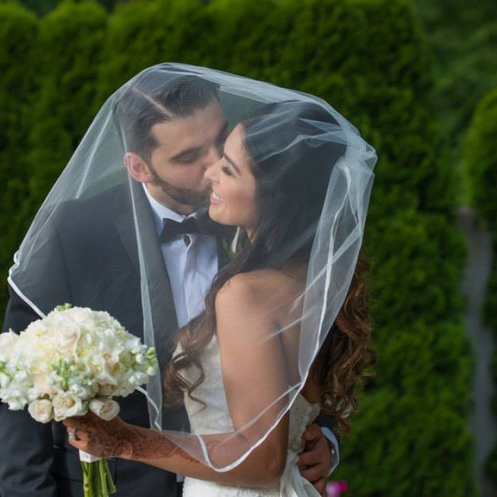 A bride and groom kissing under a veil