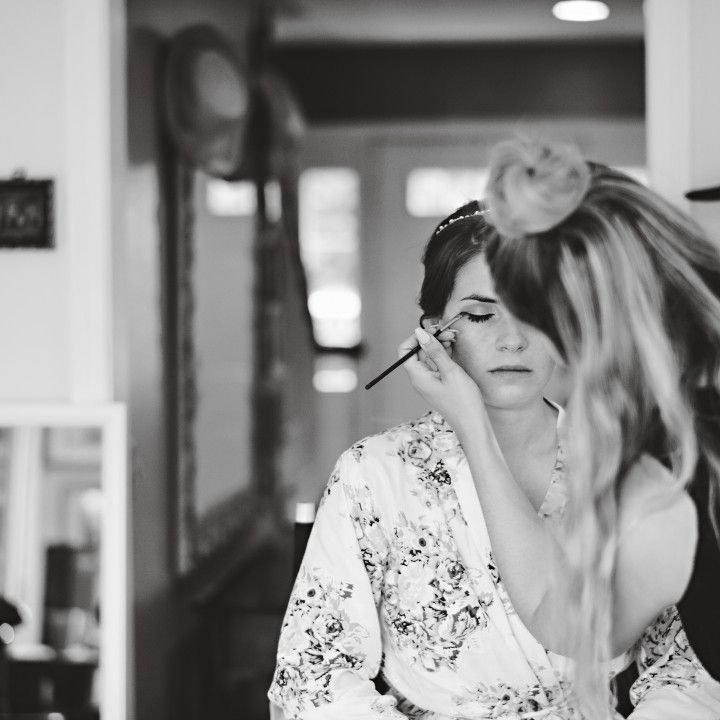 A woman is applying makeup to another woman 's face in a black and white photo.
