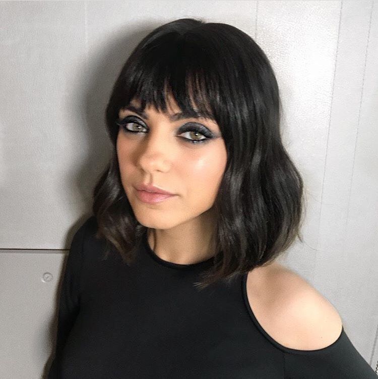 a woman with black hair and bangs is wearing a black top