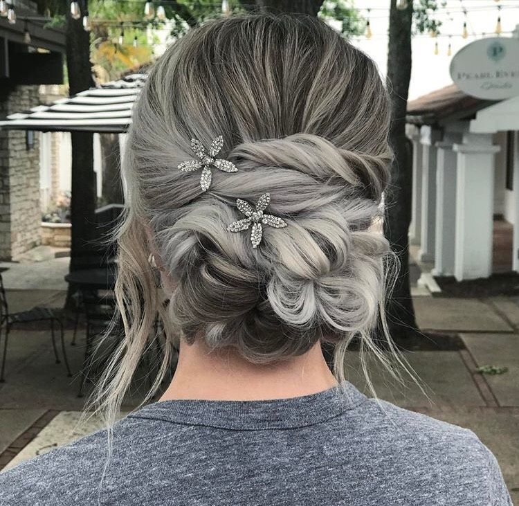 a woman with gray hair is wearing a bun with flowers in it