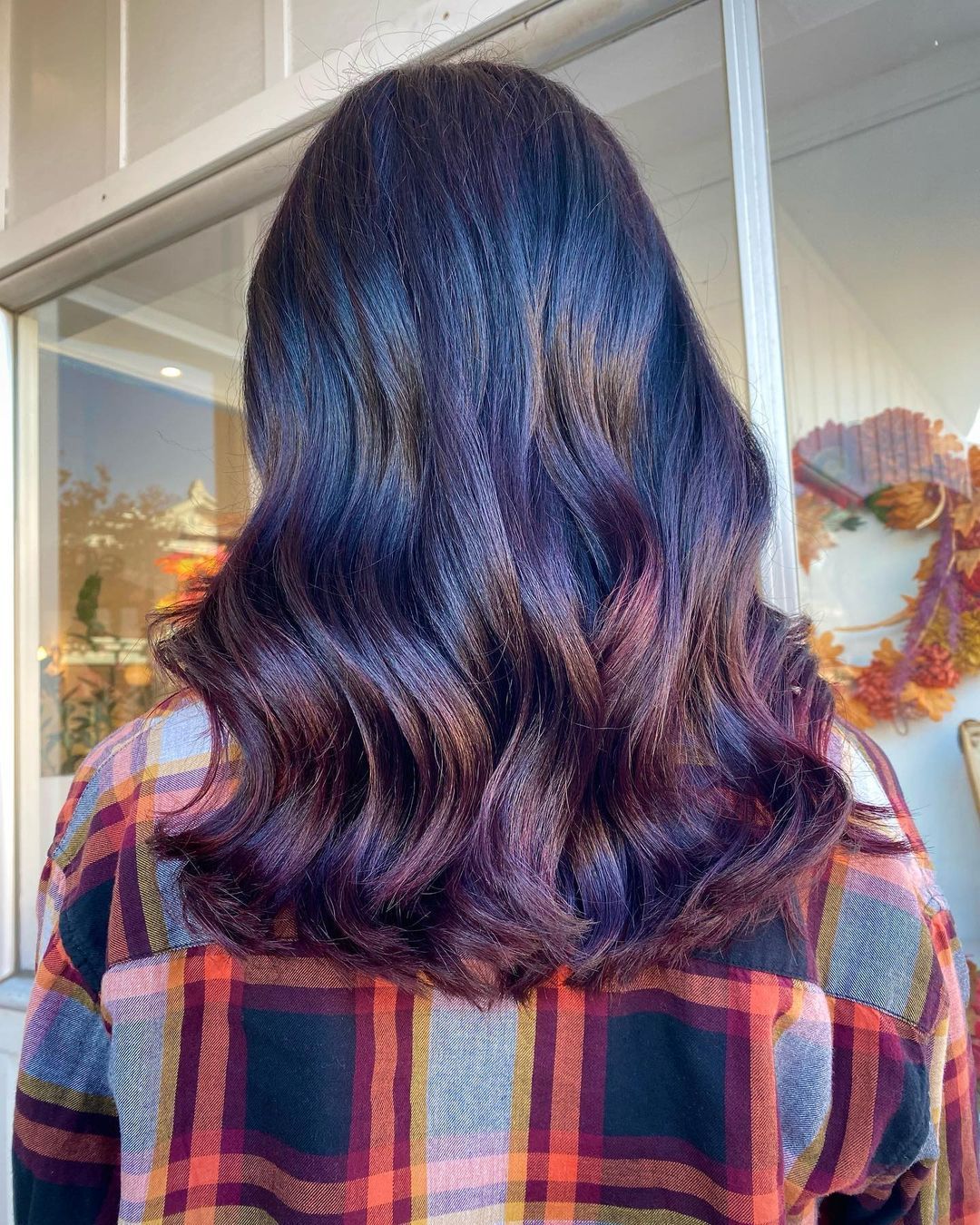 a woman with purple hair is wearing a plaid shirt