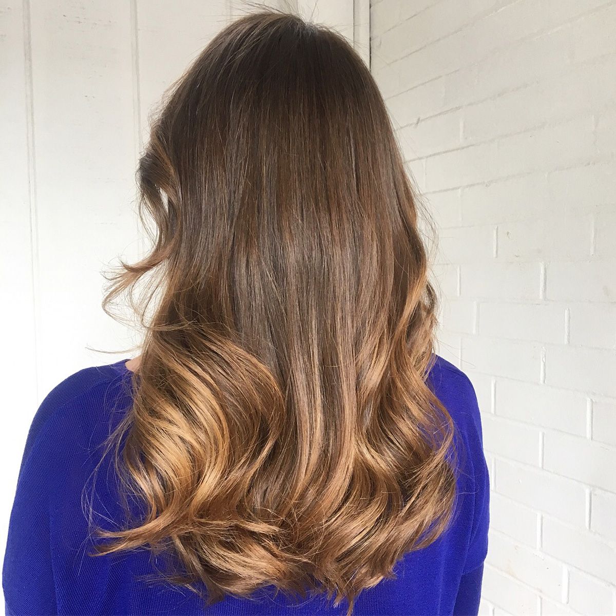 A woman with long brown hair is wearing a blue sweater.