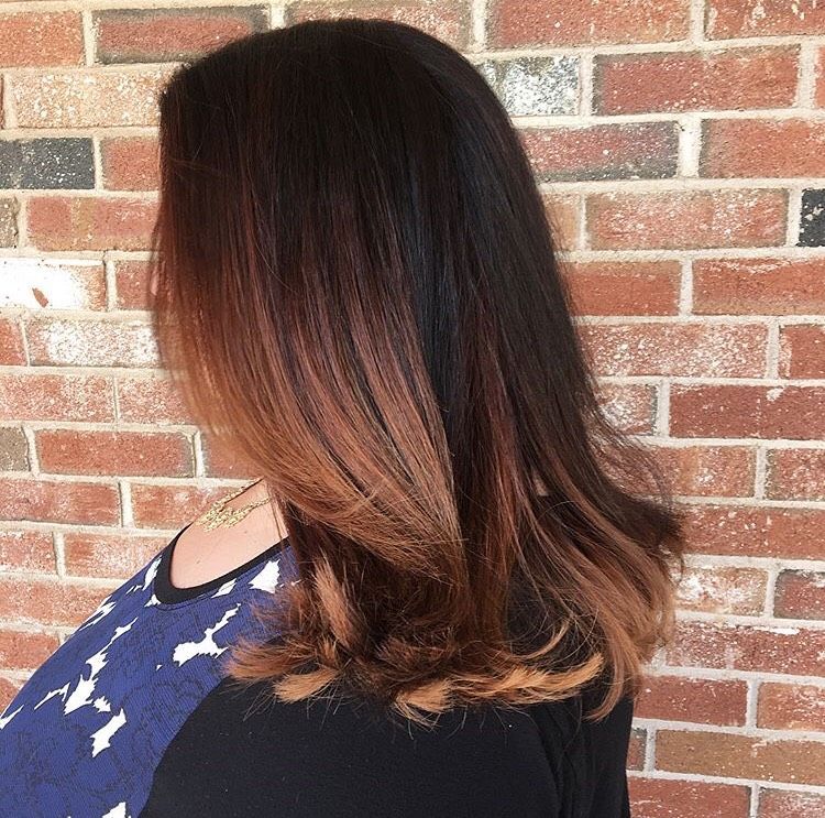 A woman with long hair is standing in front of a brick wall