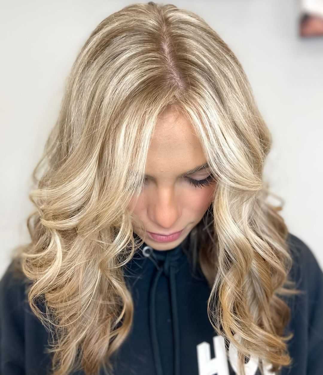 a woman with blonde hair is wearing a black hoodie with the letter h on it