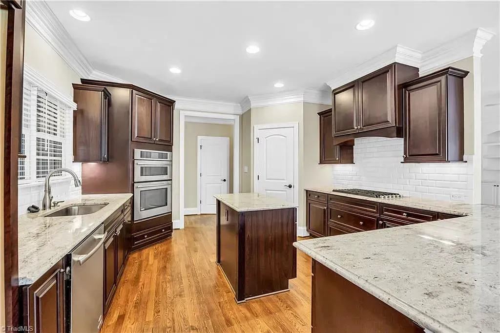 A kitchen with wooden cabinets , granite counter tops , and stainless steel appliances.