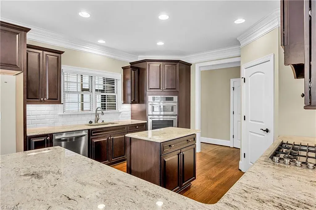 A kitchen with granite counter tops , stainless steel appliances , and brown cabinets.