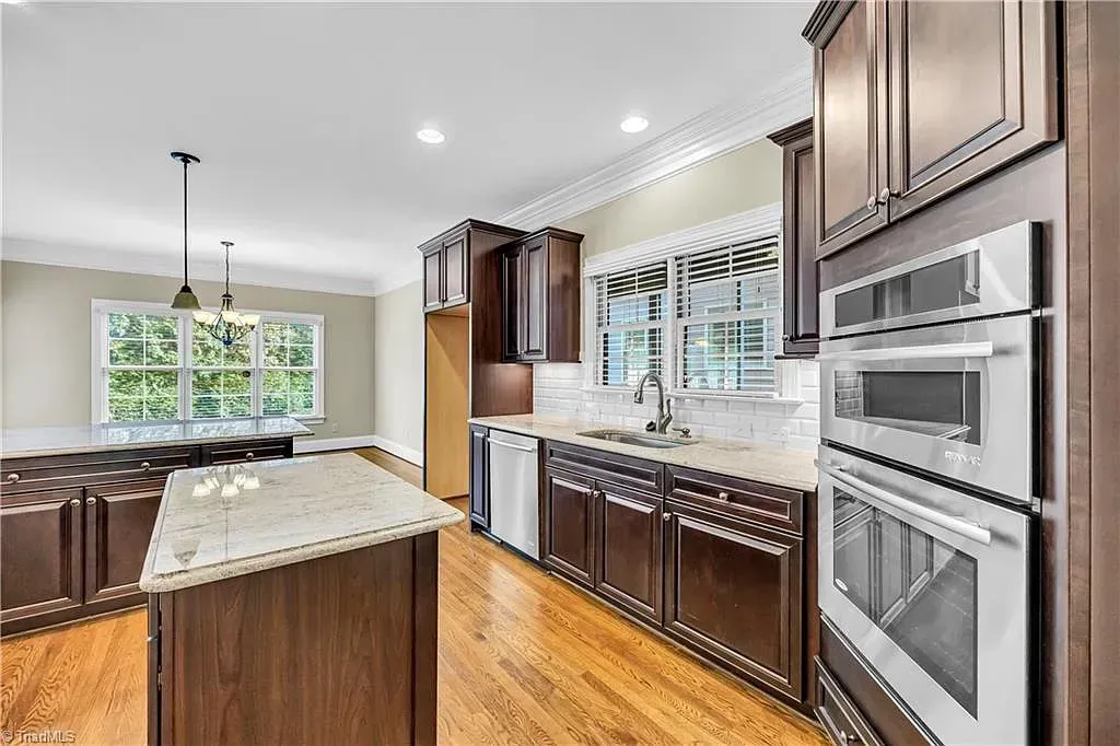 A kitchen with wooden cabinets , stainless steel appliances , and a large island.